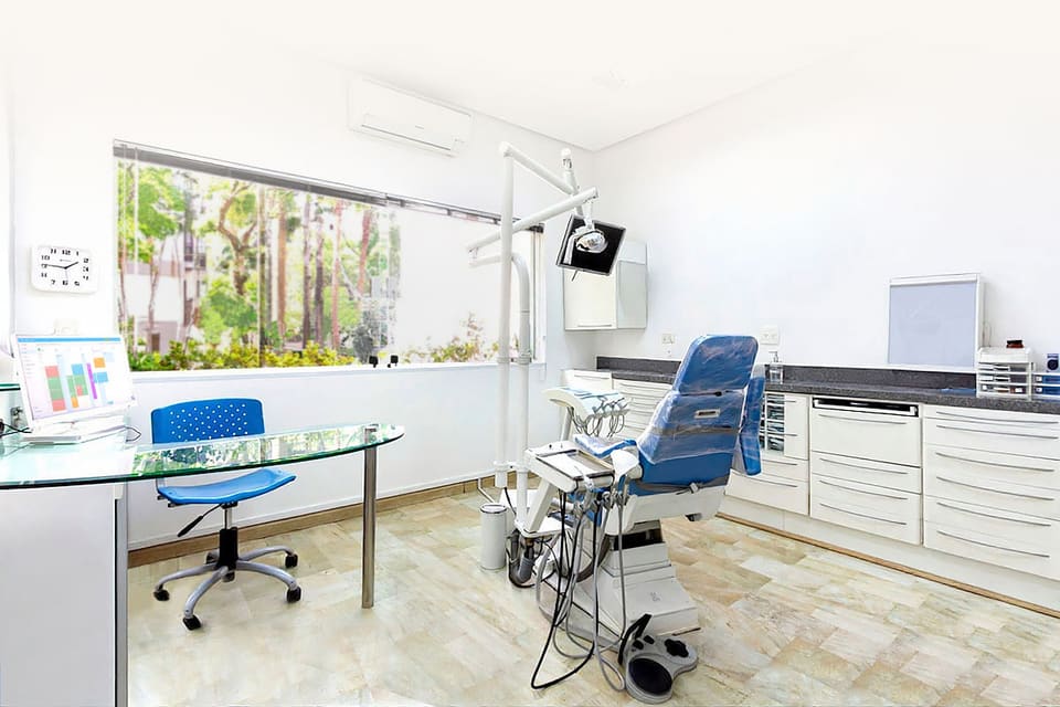 Sala clínica da Liodonto em Moema com cadeira odontológica, bancada e ampla janela com vista verde
